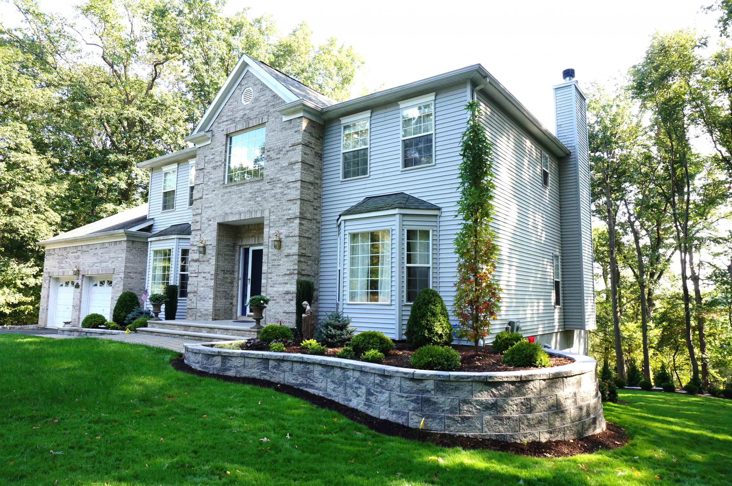 Retaining wall curving around the house with large tree in front