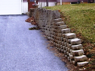 An unsafe, tilting driveway retaining wall example. An unsafe, tilting driveway retaining wall example.