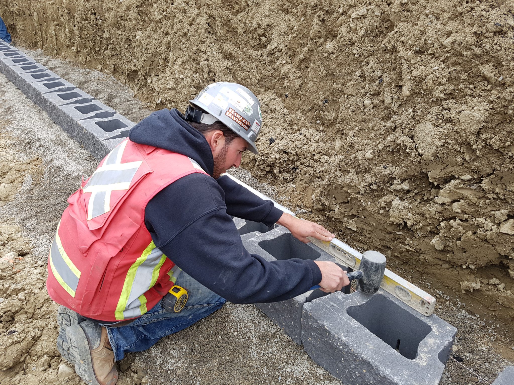 Measuring and leveling base blocks are critical to retaining wall longevity.