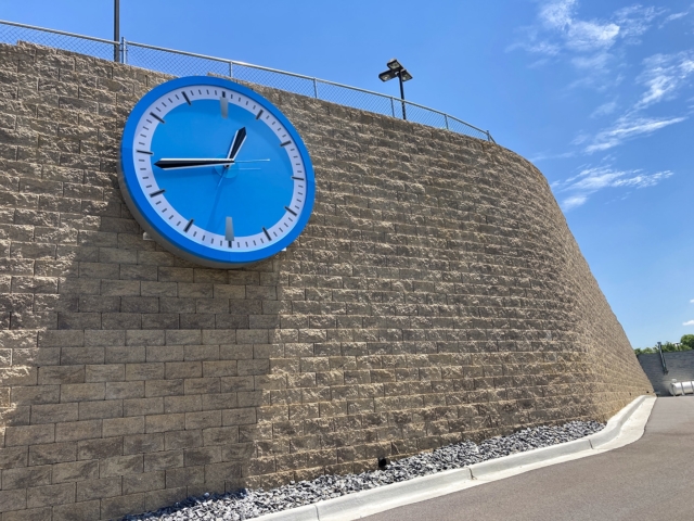 Tall CornerStone 100 retaining wall with blue clock mounted.